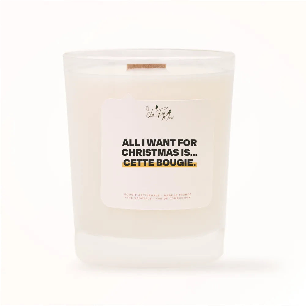 Bougie parfumée Les Fées Mères avec l'étiquette « All I want for Christmas is... cette bougie », pot blanc et mèche en bois de hêtre