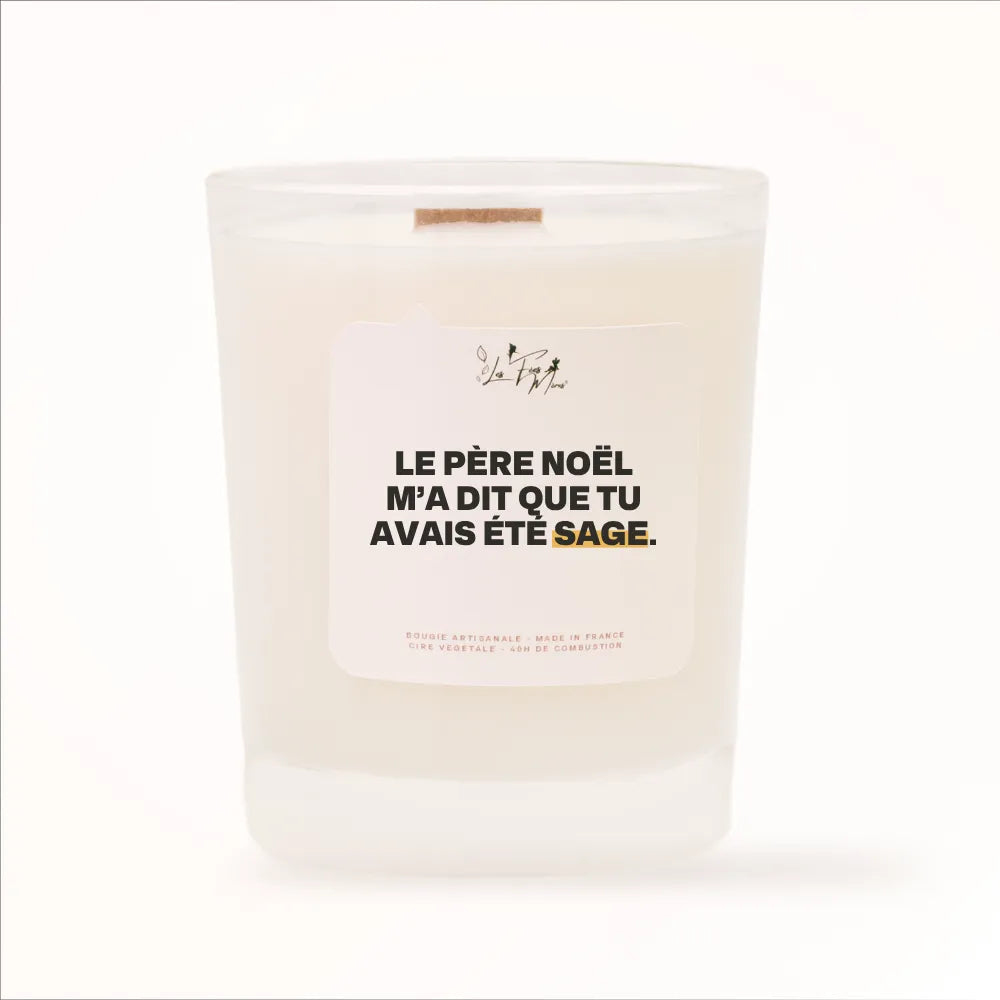 Bougie parfumée Les Fées Mères avec l'étiquette « Le Père Noël m'a dit que tu avais été sage », pot blanc et mèche en bois de hêtre