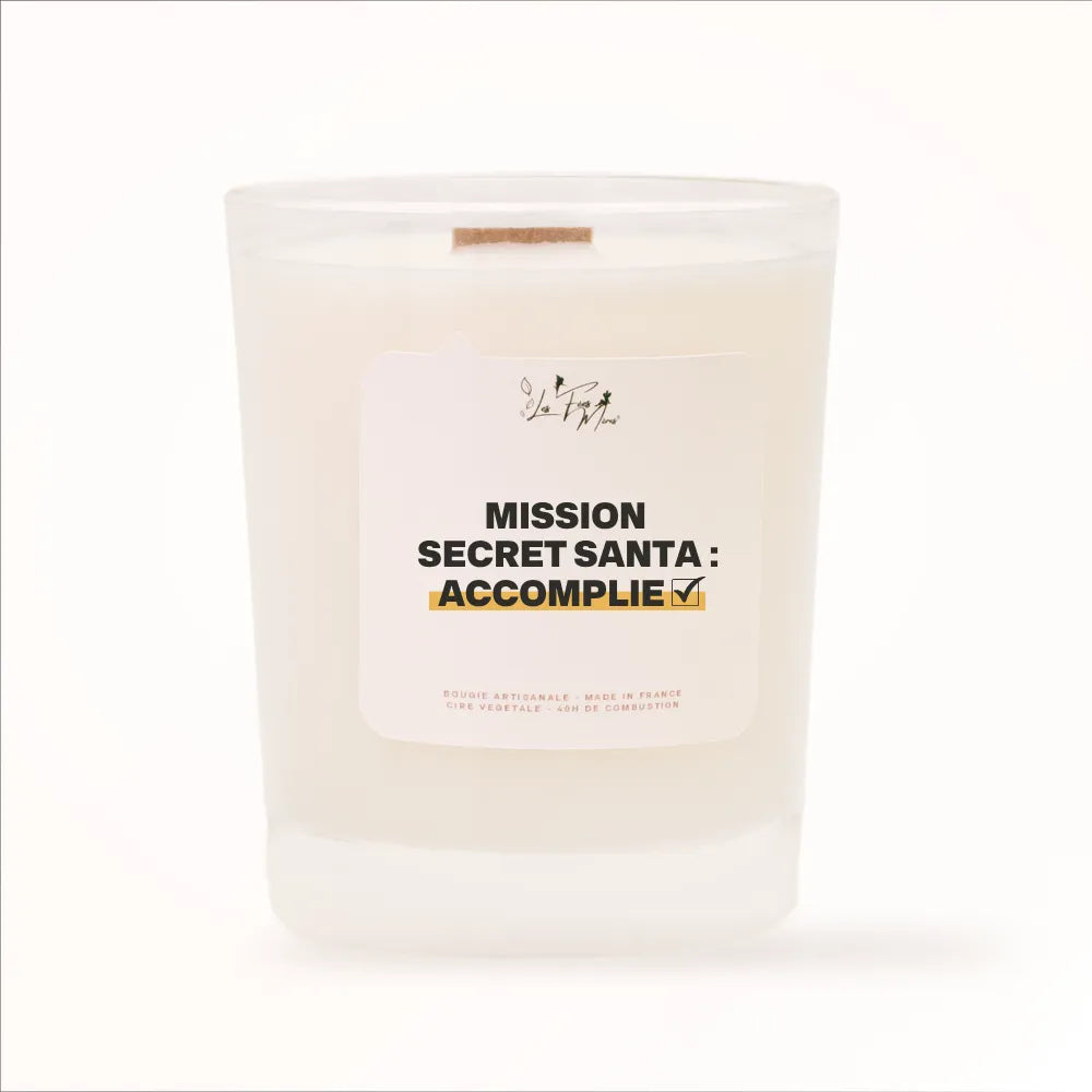 Bougie parfumée Les Fées Mères avec l'étiquette « Mission Secret Santa : accomplie », pot blanc et mèche en bois de hêtre