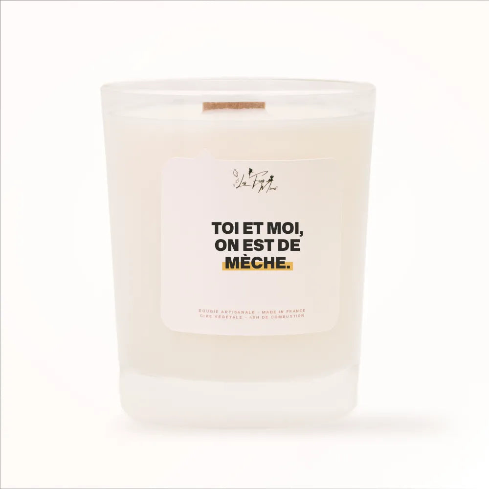 Bougie parfumée Les Fées Mères avec l'étiquette « Toi et moi, on est de mèche », pot blanc et mèche en bois de hêtre