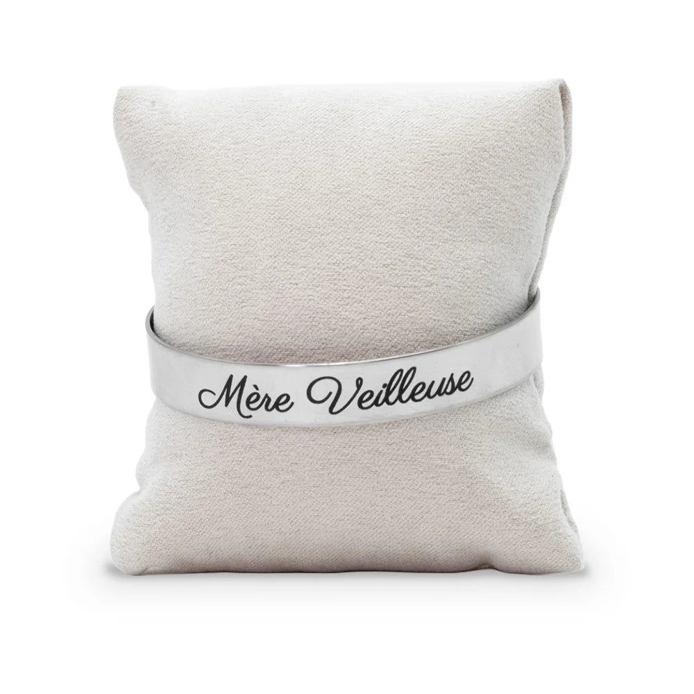 Bracelet jonc gravé Mère Veilleuse en écriture manuscrite noire sur acier inoxydable, présenté sur un coussin en tissu beige, Les Fées Mères