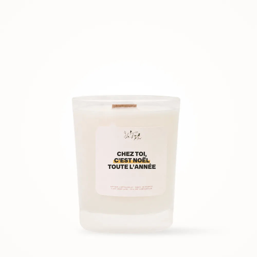 Petite bougie parfumée Les Fées Mères avec l'étiquette « Chez toi, c'est Noël toute l'année », petit format 20 heures, pot en verre blanc et mèche en bois de hêtre