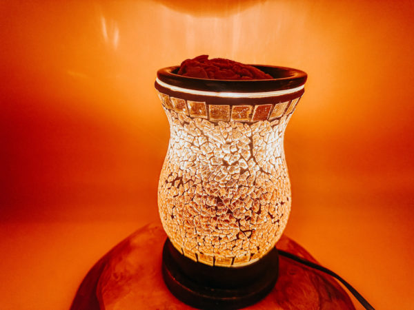 Cette photo représente un diffuseur électrique mosaïque doré permettant de fondre les fondants parfumés Les Fées Mères. Vue Allumée de nuit on voit le relief du verre.