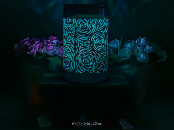 Cette photo représente le diffuseur électrique bouquet de rose allumé en bleu ciel dans le noir cela montre l'ambiance que cela apporte.