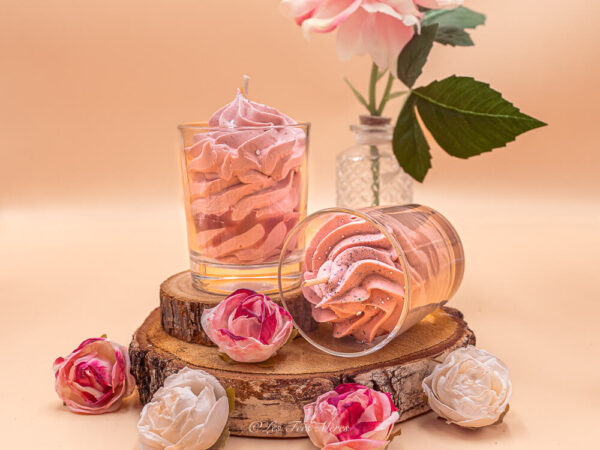 Bougie gourmande champagne artisanale en cire végétale Ecocert, parfumée aux notes pétillantes d’agrumes et de fleurs blanches, avec un design en chantilly rose poudrée et paillettes dans un verre transparent.